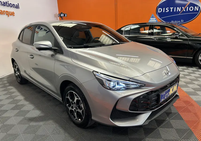 Vue 3/4 avant d'une MG3 Cosmic Silver 2026 avec phares allumés et jantes noires à motif distinctif.