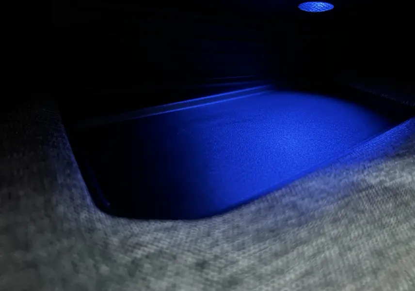 Gros plan intérieur sur un espace de rangement éclairé en bleu dans un Peugeot 5008 Hybrid gris titane.