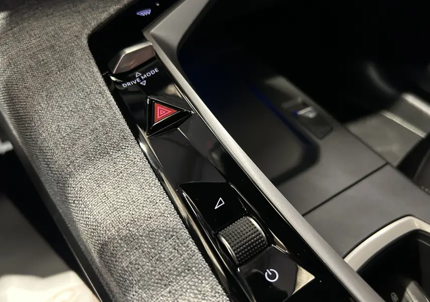 Détail de la console centrale du Peugeot 5008 Hybrid gris titane, avec boutons Drive Mode et alerte triangle rouge.