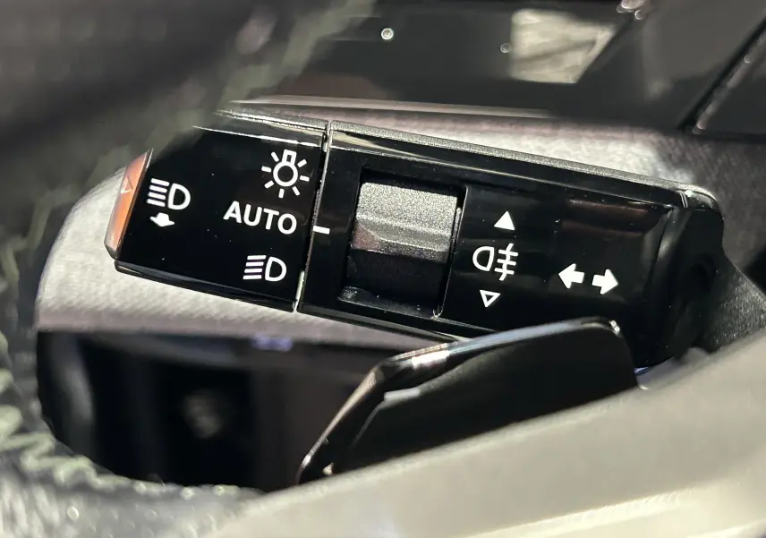 Gros plan sur la commande des phares et clignotants du Peugeot 5008 Hybrid gris titane, intérieur noir.