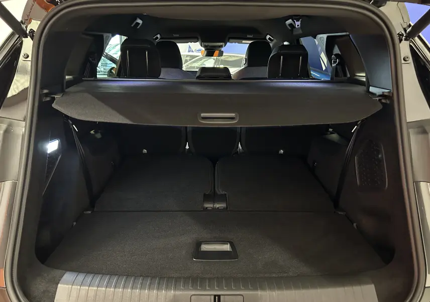 Vue arrière du coffre ouvert du Peugeot 5008 gris titane, avec banquette arrière rabattue et cache-bagages déployé.