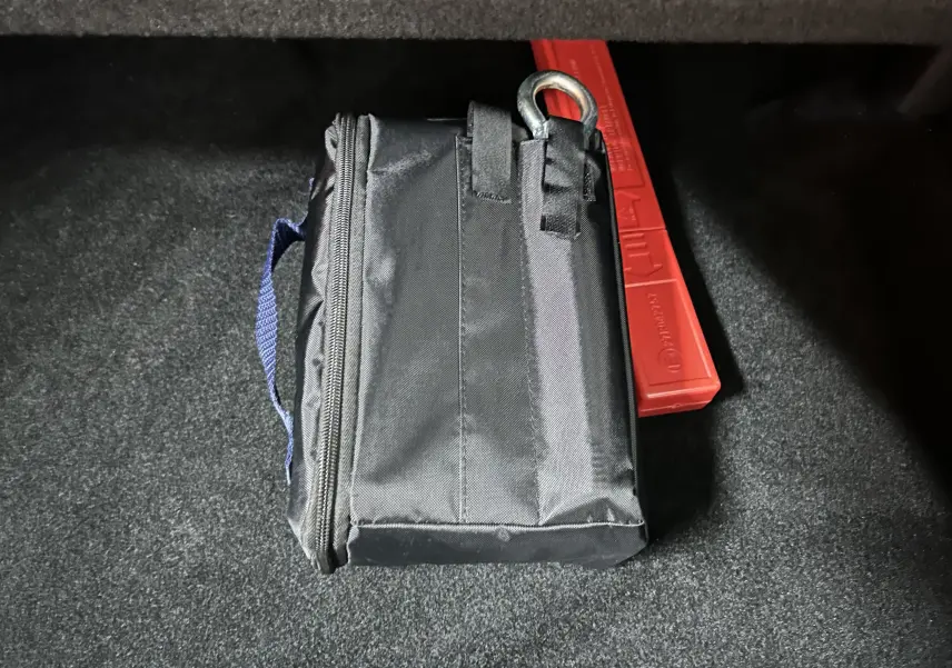 Vue rapprochée du coffre d’un Peugeot 5008 gris titane, montrant une trousse noire et un triangle de signalisation rouge.