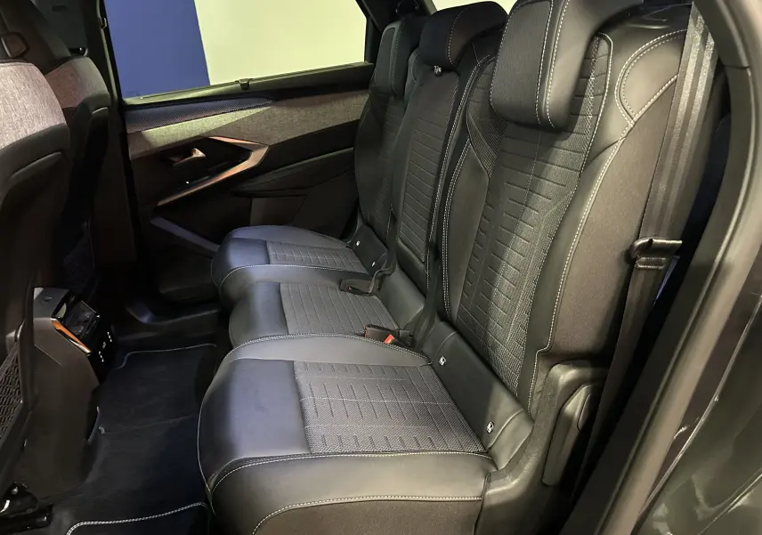 Vue latérale intérieure des sièges arrière noirs avec surpiqûres blanches du Peugeot 5008 Hybrid 2025 gris titane.