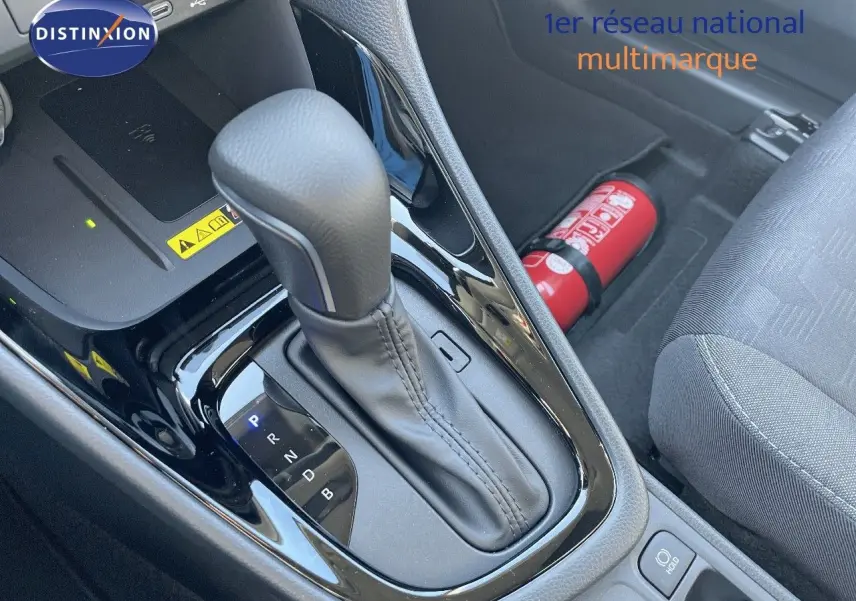 Le levier de vitesses automatique noir de la Toyota Yaris Hybrid 116ch vu en gros plan côté conducteur avec extincteur rouge visible.