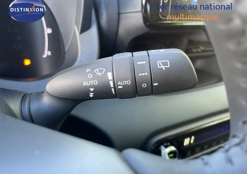 Gros plan sur la commande d'essuie-glace automatique à gauche du volant d'une Toyota Yaris Hybrid 2025 noire.