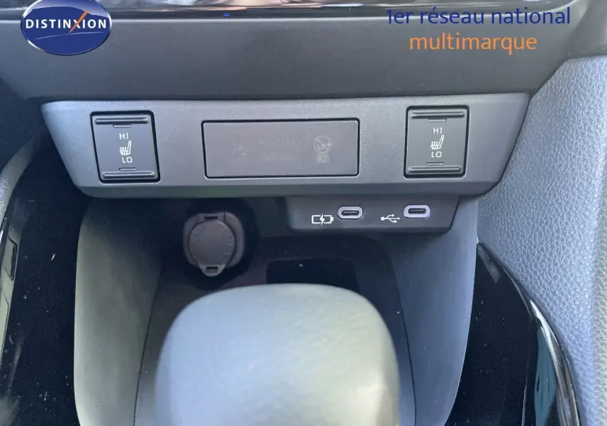 Gros plan sur la console centrale de la Toyota Yaris Hybrid 2025, montrant les commandes de siège chauffant et ports USB.