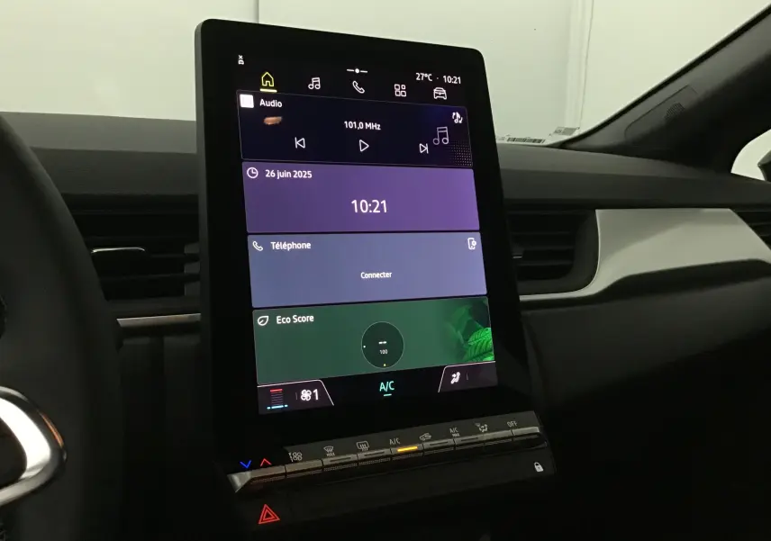 Vue rapprochée de l'écran tactile vertical du tableau de bord du Renault Captur 2025 noir/gris perle, affichant radio et climatisation.