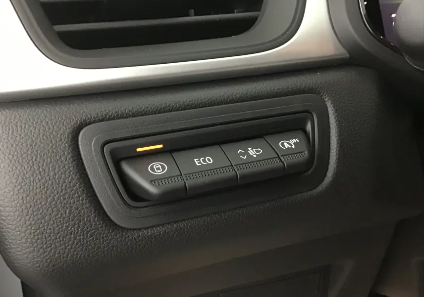 Panneau de commandes intérieur du Renault Captur 2025, boutons ECO et réglage des phares avec témoin orange allumé.