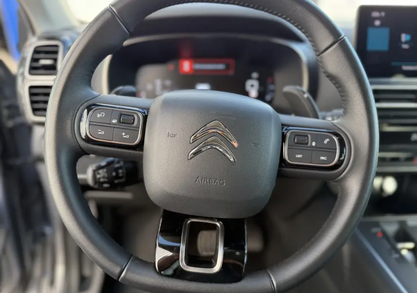 Volant en cuir noir de Citroën C5 Aircross 2024 avec commandes intégrées et logo chromé au centre.