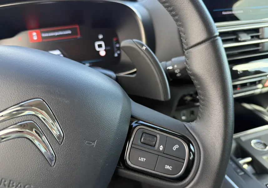Gros plan sur le volant en cuir noir du Citroën C5 Aircross 2024 avec commandes intégrées et palettes au volant.