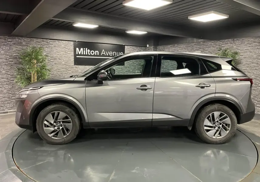 Profil côté gauche d'un Nissan Qashqai gris 2023 en showroom, soulignant ses lignes modernes et jantes alliage 17 pouces.