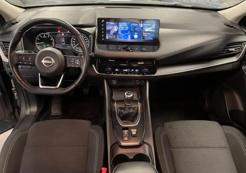 Intérieur noir du Nissan Qashqai 2023, vue frontale sur le tableau de bord avec écran tactile et levier de vitesses manuel.