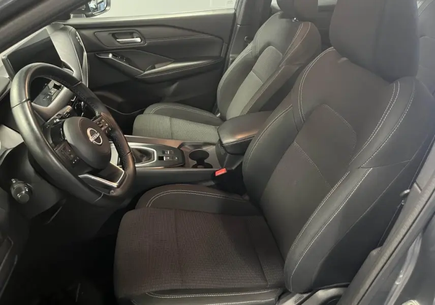 Intérieur côté conducteur du Nissan Qashqai 1.3 Mild Hybrid 2023 avec sièges tissu noir et volant cuir.