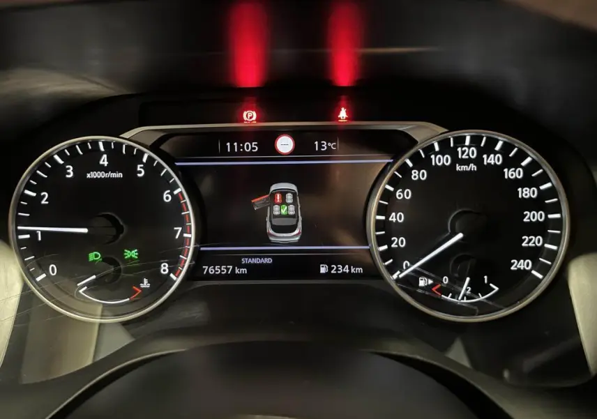 Tableau de bord du Nissan Qashqai 2023 montrant compte-tours, vitesse, et écran central avec alertes et kilométrage.