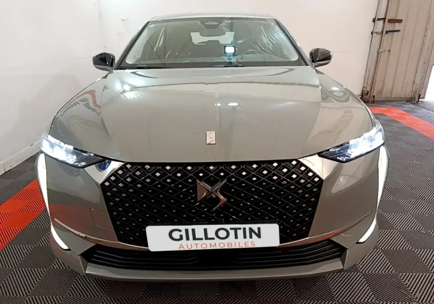 Vue avant du DS4 E-TENSE 225 TROCADERO gris foncé avec calandre noire et phares LED allumés dans un garage.