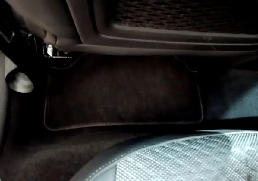 Vue intérieure du plancher côté passager avant du DS4 E-TENSE 225 TROCADERO gris foncé avec tapis de sol noir.