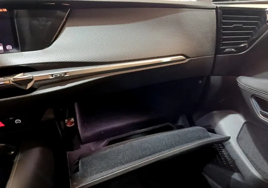 Intérieur du DS4 E-TENSE 225 TROCADERO 2023, vue côté passager sur tableau de bord et boîte à gants ouverte noire.