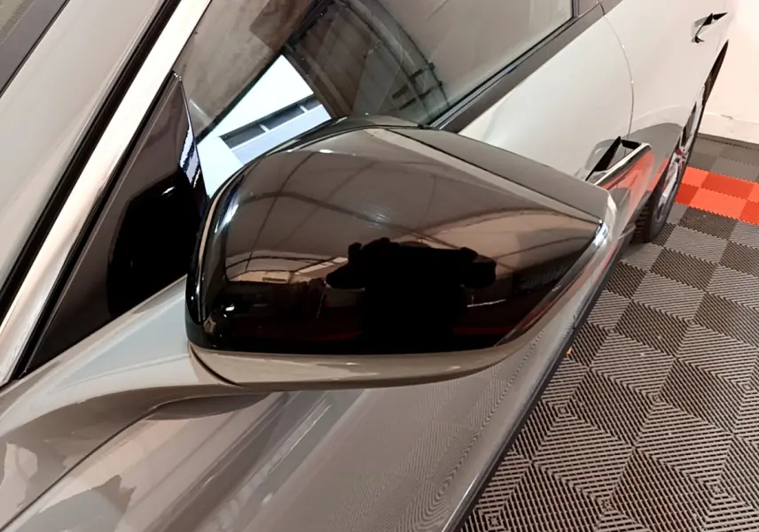 Rétroviseur noir brillant côté gauche du DS4 E-TENSE gris foncé, vue rapprochée sur la portière avant.