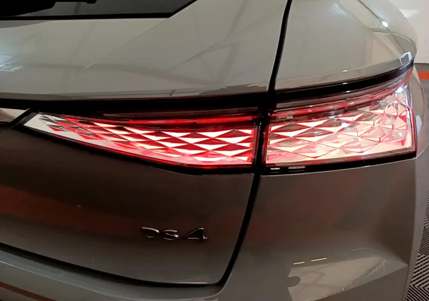 Gros plan sur le feu arrière droit rouge et blanc du DS4 gris foncé, avec le logo DS4 visible sur le coffre.