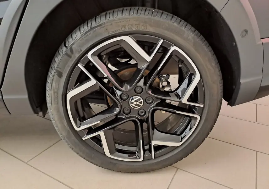 Gros plan sur la jante alliage noir et argentée du côté arrière droit d’un Volkswagen Taigo noir intense nacré.