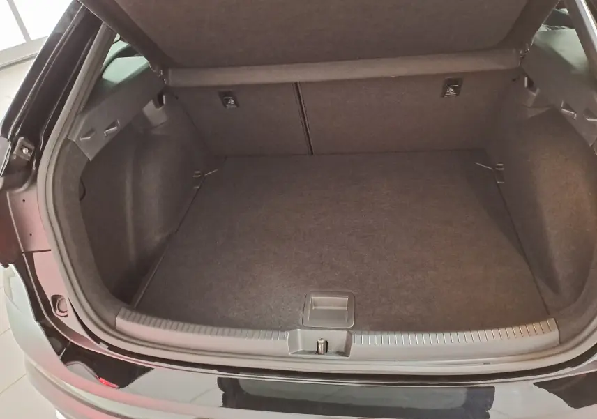 Coffre ouvert vu de l'arrière d'un Volkswagen Taigo noir intense nacré, montrant un espace de chargement vide et propre.