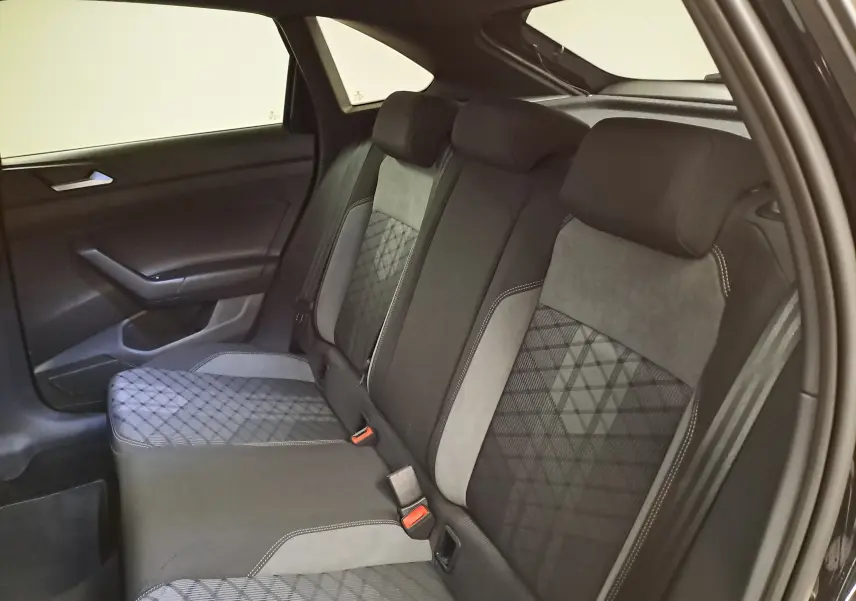 Vue intérieure côté gauche sur la banquette arrière du Volkswagen Taigo 1.5 TSI R-Line noir intense nacré avec sièges bi-matière gris et noir.