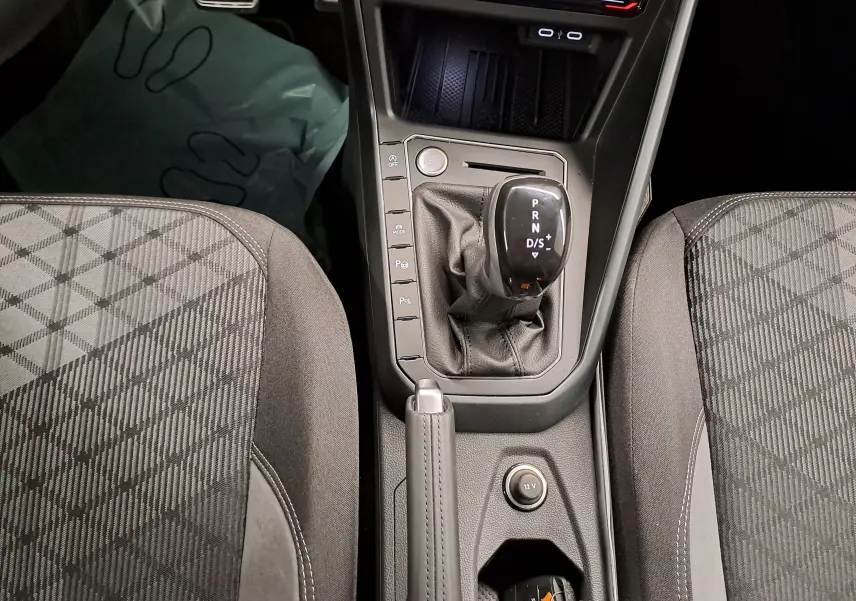 Vue rapprochée du levier de vitesse automatique et frein à main cuir entre les sièges avant gris à motifs du Volkswagen Taigo 2025.