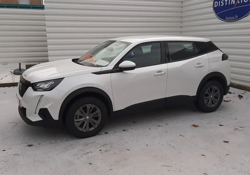 Peugeot 2008 blanc en vue 3/4 avant droit, avec toit noir et jantes foncées sur parking extérieur.