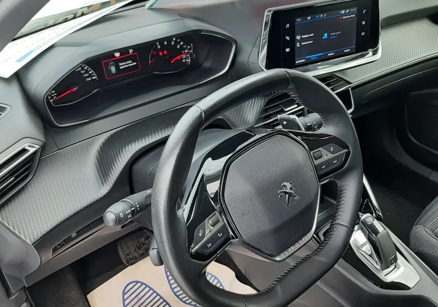 Vue intérieure côté conducteur du tableau de bord et volant Peugeot 2008 blanc avec écran tactile et finition carbone.