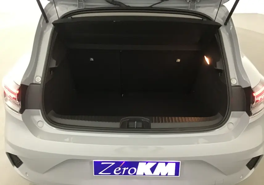 Coffre ouvert vu de l'arrière d'une Renault Clio V gris Rafale, avec feux arrière allumés et plaque Zero KM.