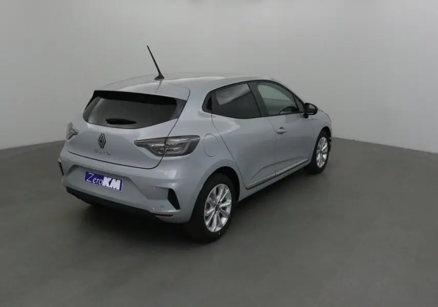 Renault Clio V gris Rafale vue 3/4 arrière droit, avec vitres teintées et protections latérales chromées visibles.