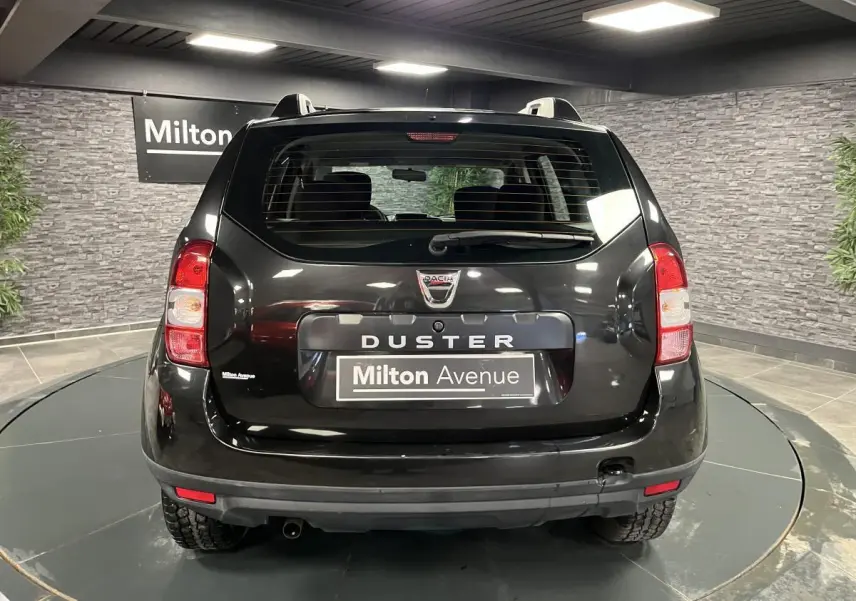 Vue arrière d'un Dacia Duster noir 2016 avec feux rouges et plaque Milton Avenue dans un showroom.