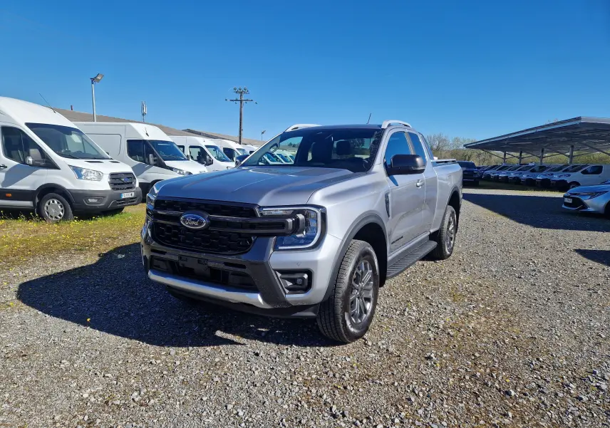 Ford Ranger Super Cabine gris iconic en 3/4 avant droit, avec calandre noire et jantes alliage visibles sur parking.
