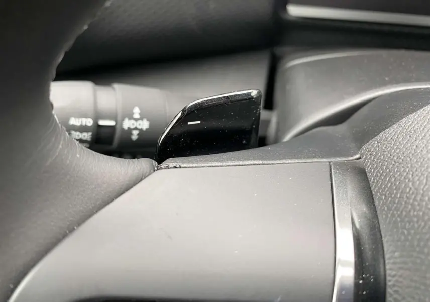 Gros plan sur la palette de changement de rapport noire au volant d'une Citroën C4 X 2022 rouge Elixir.