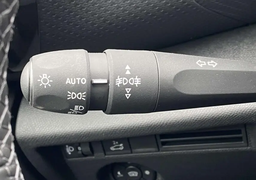 Gros plan sur la manette de commande des feux et clignotants dans l'habitacle d'une Citroën C4 X rouge Elixir.