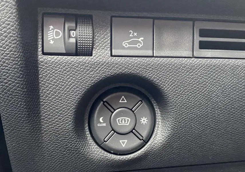 Gros plan sur les commandes de réglage des rétroviseurs et des phares dans une Citroën C4 X rouge Elixir 2022.