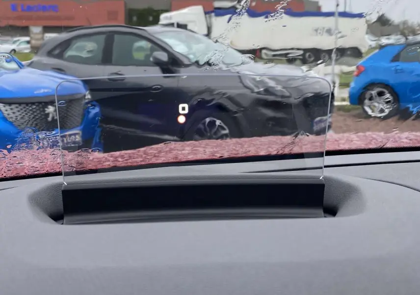 Affichage tête haute transparent du Citroën C4 X rouge Elixir, vue intérieure sur tableau de bord et pare-brise humide.