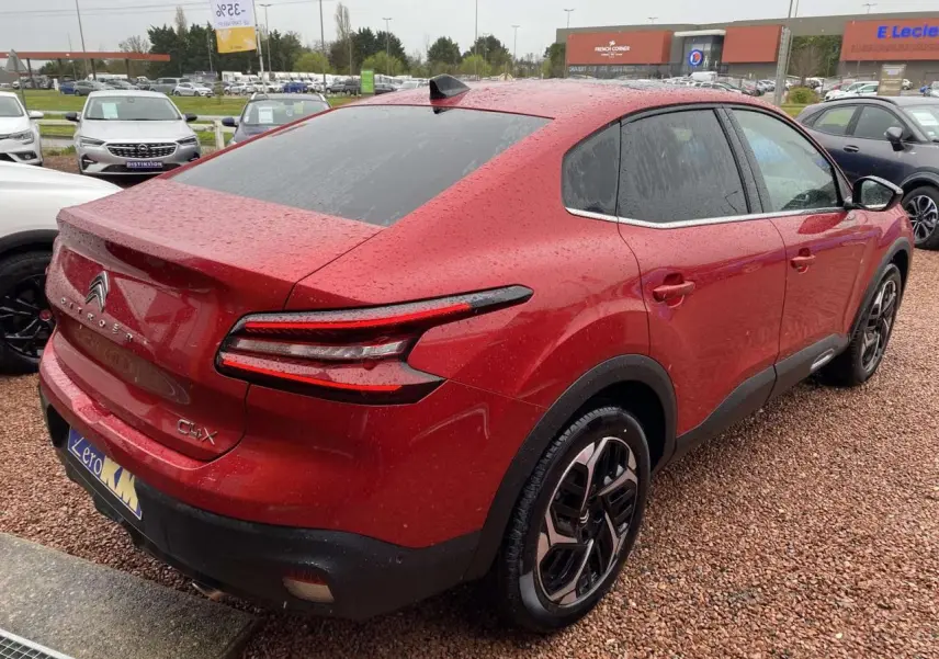 Vue 3/4 arrière droite d'une Citroën C4 X rouge Elixir avec toit ouvrant et jantes alliage 18 pouces.