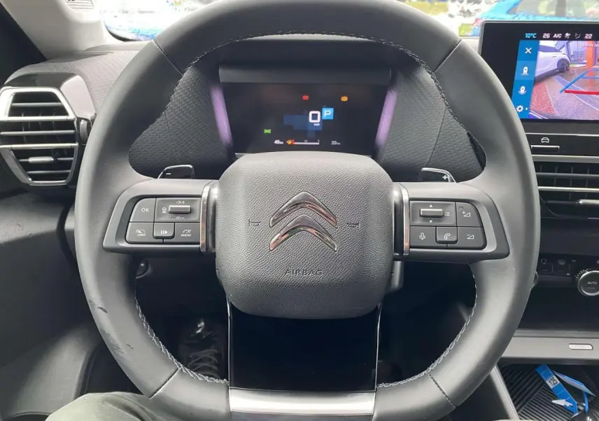 Vue rapprochée du volant Citroën C4 X 2022 avec commandes intégrées et tableau de bord numérique allumé.