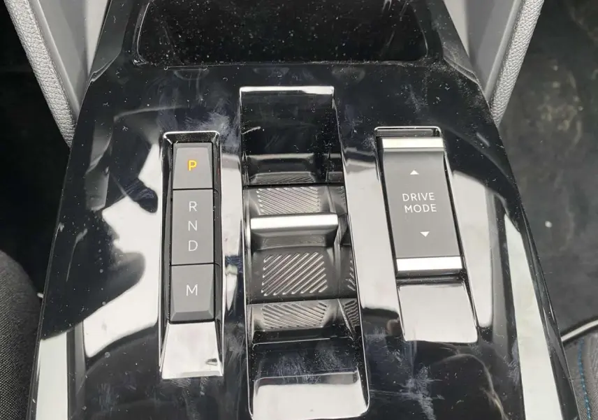 Gros plan sur la console centrale noire brillante de la Citroën C4 X avec commandes de boîte auto et mode de conduite.