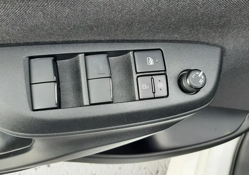 Gros plan sur les commandes de lève-vitres et réglage des rétroviseurs côté conducteur d’une Toyota Yaris blanche 2023.