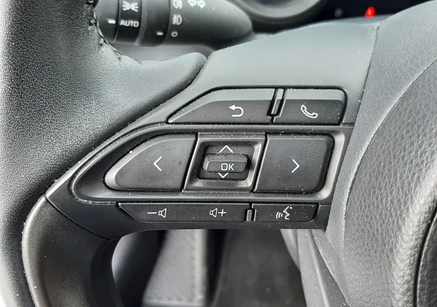 Gros plan sur les commandes multifonctions noires au volant côté gauche de la Toyota Yaris hybride 2023.