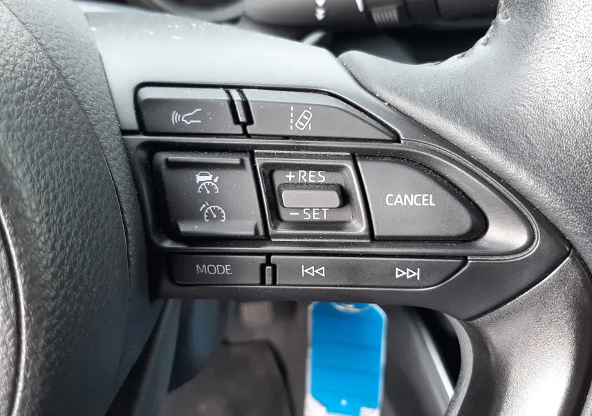 Gros plan sur les commandes multifonctions à droite du volant noir de la Toyota Yaris hybride 2023.