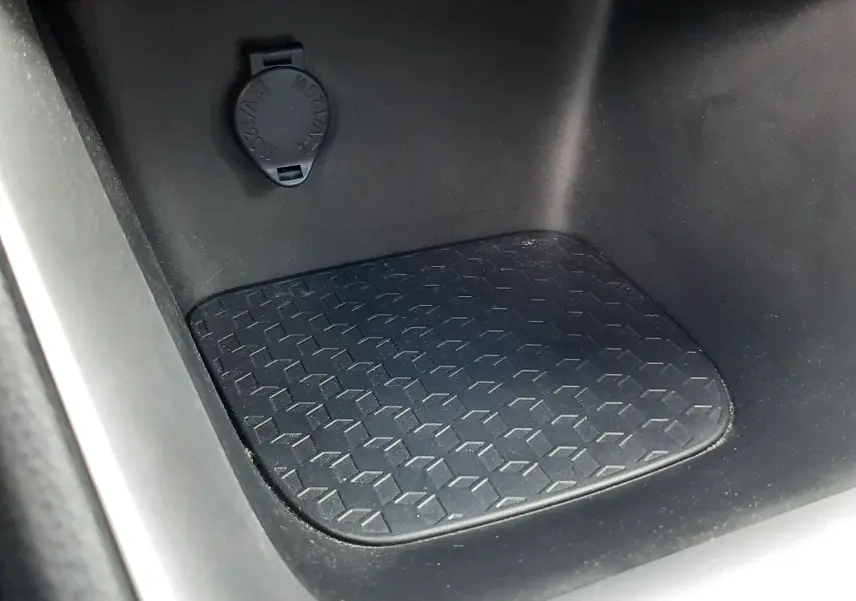 Détail de la console centrale noire de la Toyota Yaris hybride 2023 avec prise 12V et surface antidérapante.