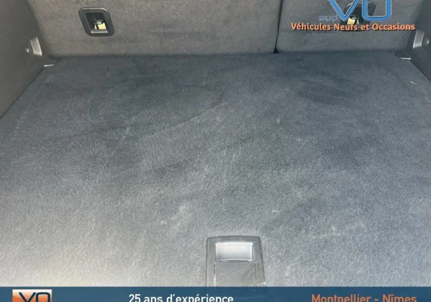 Coffre spacieux et vide du Jeep Compass blanc 2024, version e-Hybrid Altitude, avec tapis noir et poignée centrale.