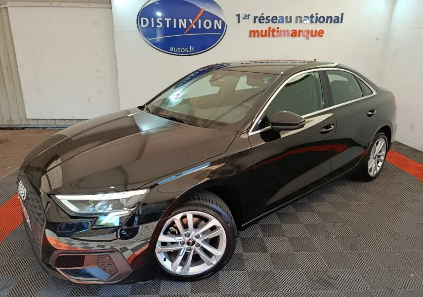 Audi A3 30 TFSI MHEV noir vue 3/4 avant droit, avec jantes argentées et phares LED allumés en intérieur showroom.