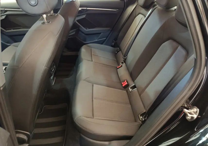Vue côté droit de la banquette arrière noire de l'Audi A3 30 TFSI MHEV avec ceintures et appuie-têtes intégrés.