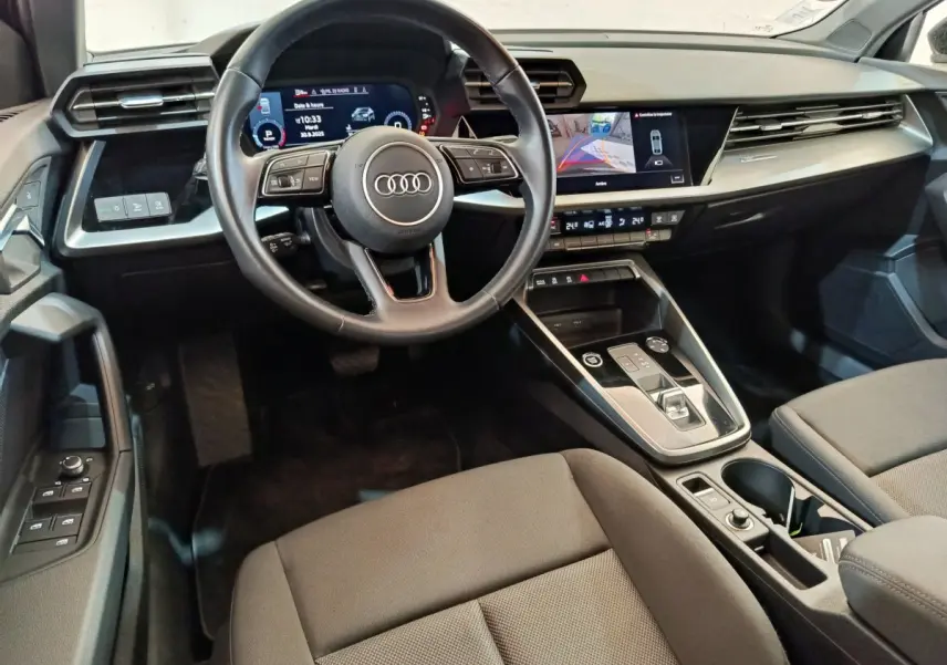Vue intérieure de l'Audi A3 30 TFSI MHEV 2022, tableau de bord et volant cuir noir avec écran tactile central.