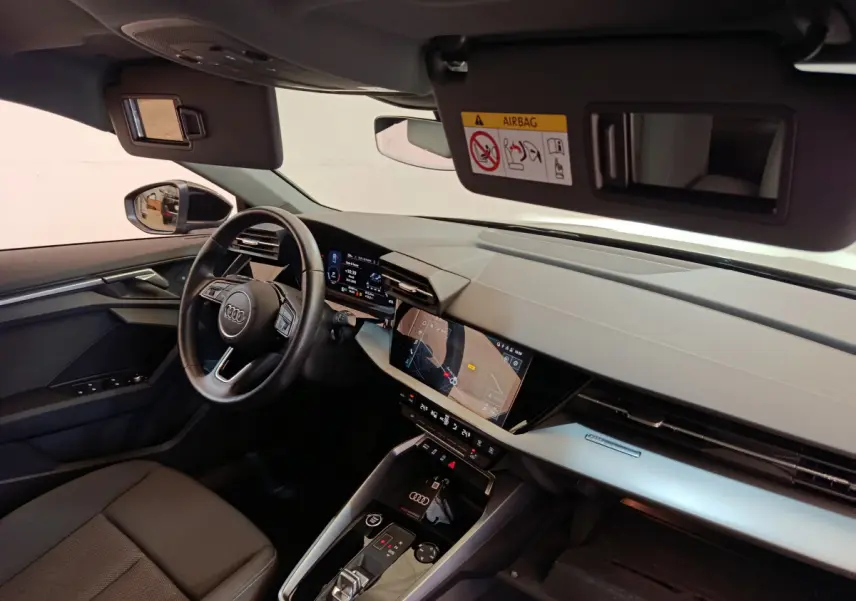 Vue intérieure côté conducteur de l'Audi A3 30 TFSI MHEV 2022, tableau de bord moderne avec écran tactile et volant cuir noir.