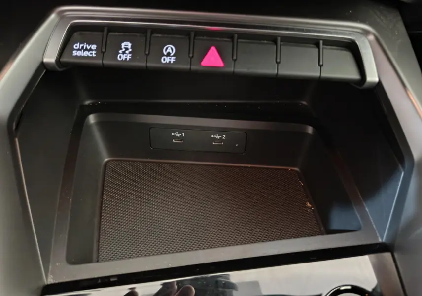 Vue rapprochée de la console centrale noire de l'Audi A3 30 TFSI MHEV avec ports USB et boutons de contrôle éclairés.